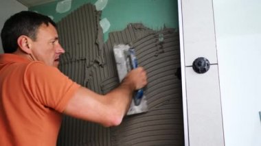 Adam duvara büyük formatlı fayanslar yerleştiriyor. konut yenileme konsepti