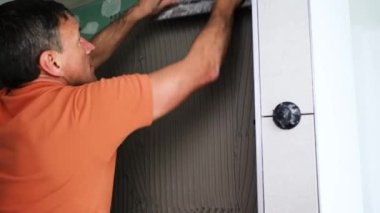 Adam duvara büyük formatlı fayanslar yerleştiriyor. konut yenileme konsepti