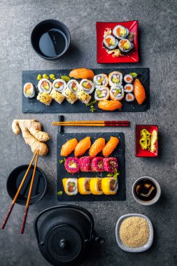 Gri yüzeyinde soya sosu ve çubuklu lezzetli suşi seti.