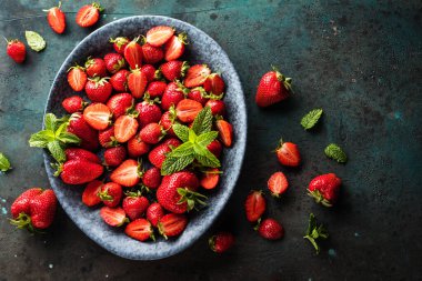 Taze olgun çileklerle dolu kasenin en üst görüntüsü.