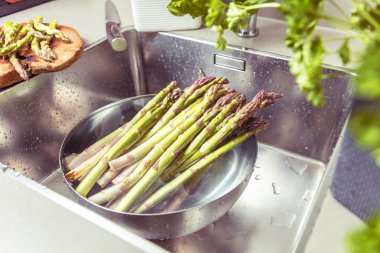 Mutfak lavabosunda yıkanan taze kuşkonmaz manzarası.