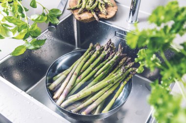 Mutfak lavabosunda yıkanan taze kuşkonmaz manzarası.