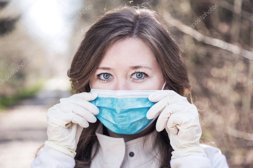 young woman wearing medical mask and protective gloves in park. corona virus protection concept