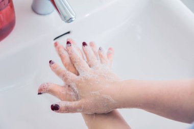 Ellerini sabunla yıkayan genç bir kadının kısmi görüntüsü