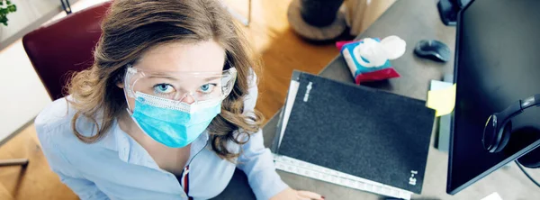 young woman in medical mask working from home