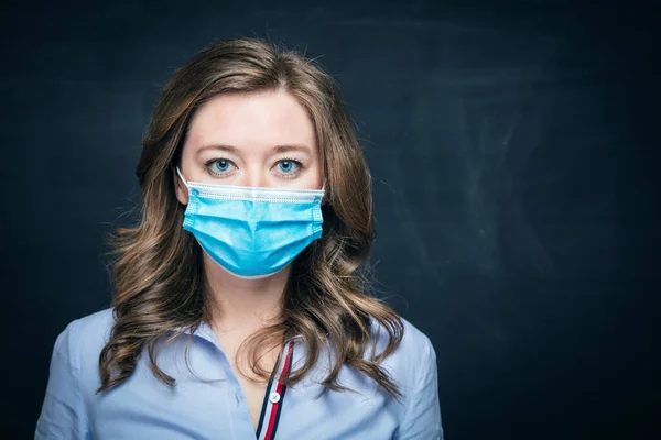 stock image young woman in medical mask looking at camera on black background