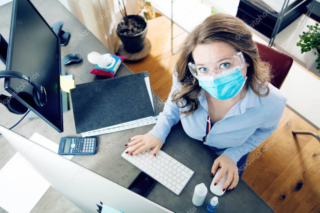 young woman in medical mask working from home