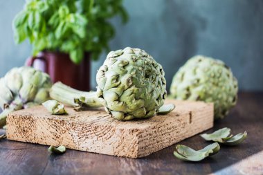 Koyu kırsal ahşap masa üzerinde taze organik enginarlar.