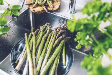 Mutfak lavabosunda yıkanan taze kuşkonmaz manzarası.