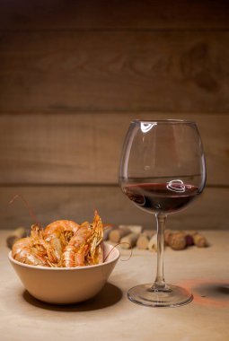 Bir kadeh kırmızı şarap ve kızarmış karides.