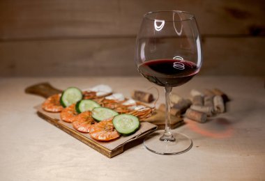 Bir kadeh kırmızı şarap ve kızarmış karides.