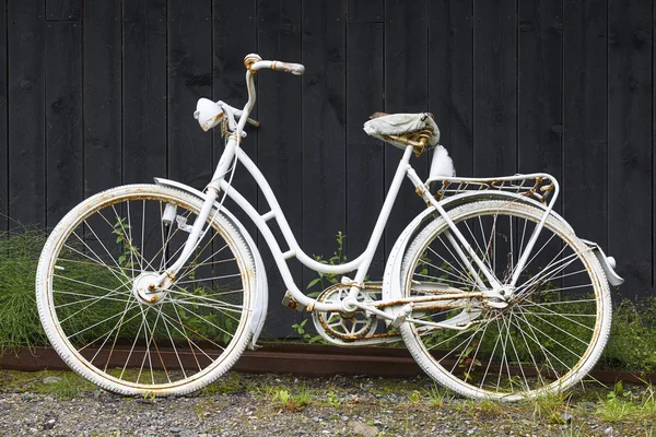 Bicicleta oxidada vieja blanca sobre una pared de madera negra. Fondo vintage — Foto de Stock