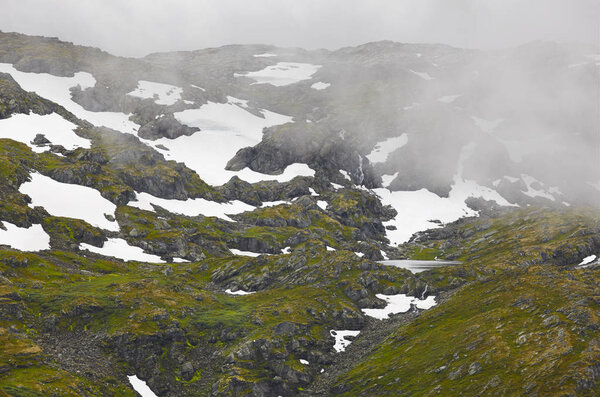 Norwegian rocky mountain landscape with snow and fog. Norway tre