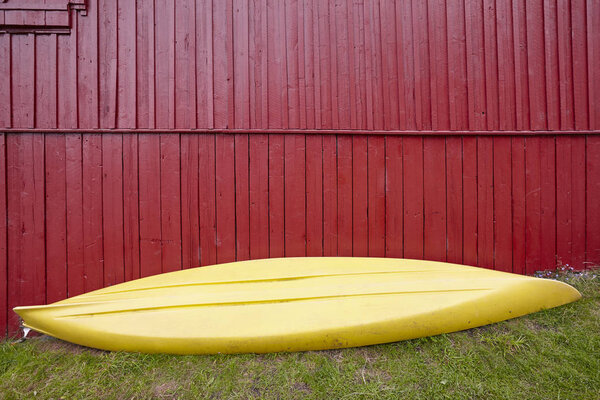 Yellow kayak over a red wooden cabin facade. Adventure sports