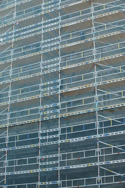 Building site facade with scaffolds and protection mesh — Stock Photo, Image