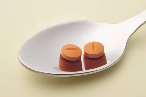 Pillole e cucchiaio dettaglio. Fondo giallo. Trattamento dei medicinali . — Foto Stock