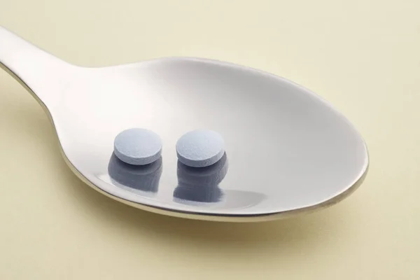 Dettaglio pillola e cucchiaio. Sfondo beige. Trattamento farmacologico. H — Foto Stock