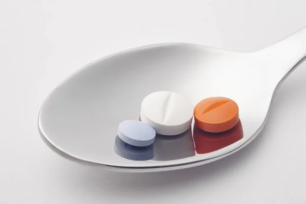 Tabletki i wszystko łyżką. Białe tło. Medycyna leczenie. — Zdjęcie stockowe