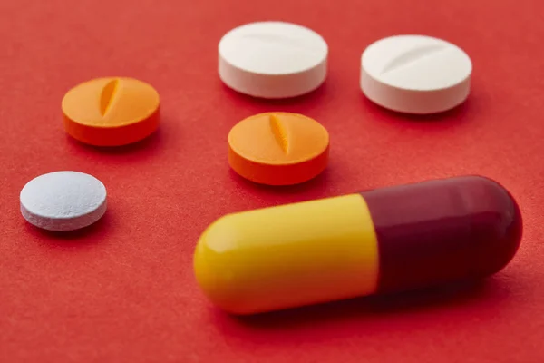 Pillole su sfondo rosso. Trattamento farmacologico. Assistenza sanitaria — Foto Stock
