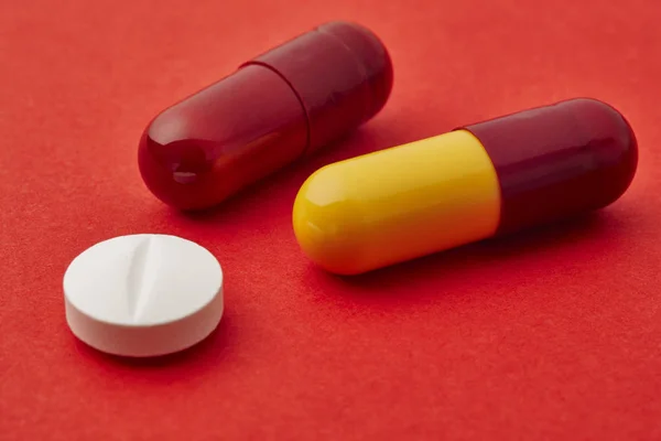 Pillole su sfondo rosso. Trattamento farmacologico. Assistenza sanitaria — Foto Stock