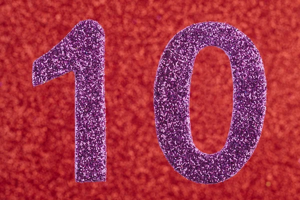 Numero dieci colore viola su uno sfondo rosso. Anniversario . — Foto Stock