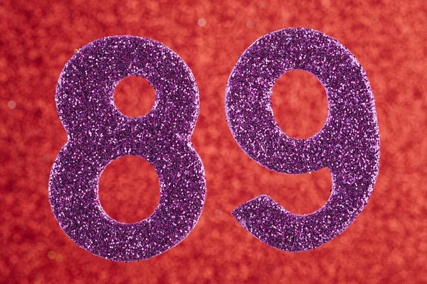 Numer osiemdziesiąt dziewięć fioletowy kolor na czerwonym tle. Anniversa — Zdjęcie stockowe