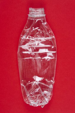 Ezilmiş plastik şişe kırmızı arka plan ile. Geri dönüşümlü çöp. 
