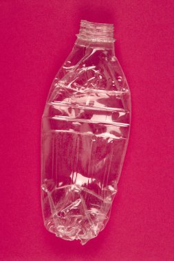 Ezilmiş plastik şişe pembe bir arka plan ile. Geri dönüşümlü çöp. V