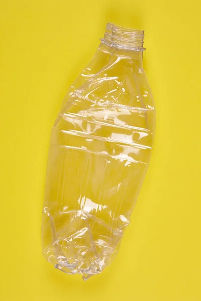 Bottiglia di plastica schiacciata con sfondo giallo. Spazzatura riciclata — Foto Stock