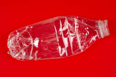Ezilmiş plastik şişe kırmızı arka plan ile. Geri dönüşümlü çöp. 