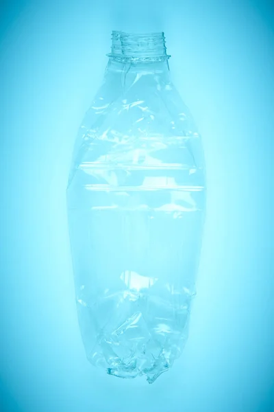 Bottiglia di plastica schiacciata con sfondo blu. Spazzatura riciclata . — Foto Stock