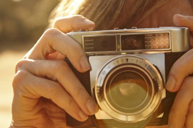 Kadın vintage fotoğraf makinesi ile fotoğraf çekmek. Arka ışık. Seyahat 