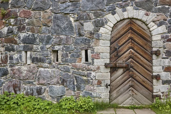 Pared de piedra con puerta de madera cerrada castillo antiguo. Vintage — Foto de Stock