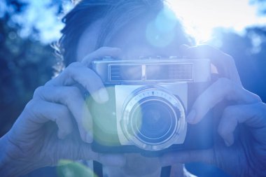 Kadın vintage fotoğraf makinesi ile fotoğraf çekmek. Arka ışık. Mavi tonu