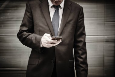 İş adamı manifatura ile hareket eden telefon. Çalışma zamanı. Açık havada