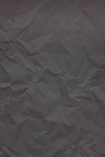 Black crumpled wrinkled textured paper background.