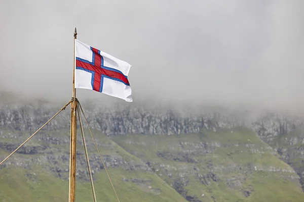 Flagge und Symbol der Färöer wehen auf der Fjordlandschaft. — Stockfoto