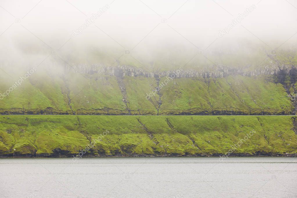 Faroe islands green landscape with fog ocean and road