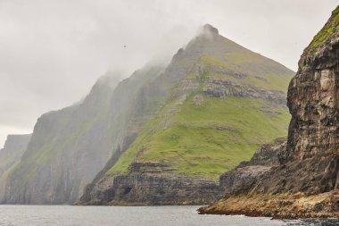 Faroe adalarındaki yeşil kayalıklar ve Atlantik Okyanusu. 