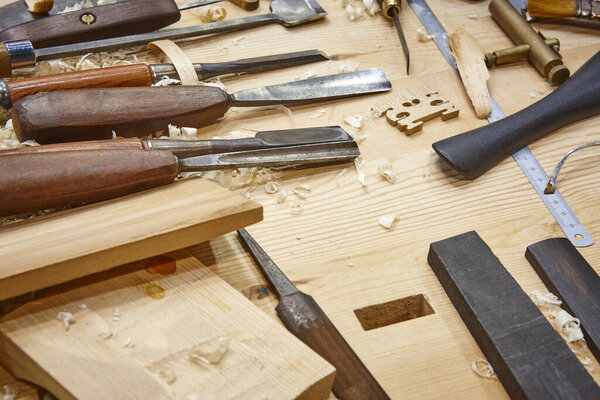 Luthier workshop with violin wooden parts and tools. Traditional craftmanship. 
