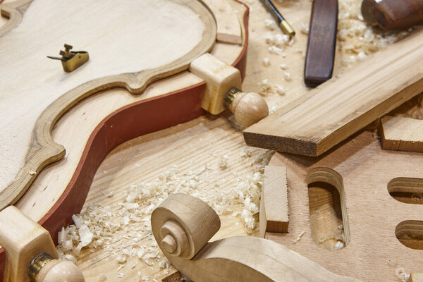 Luthier workshop with violin wooden parts and tools. Traditional craftmanship. 