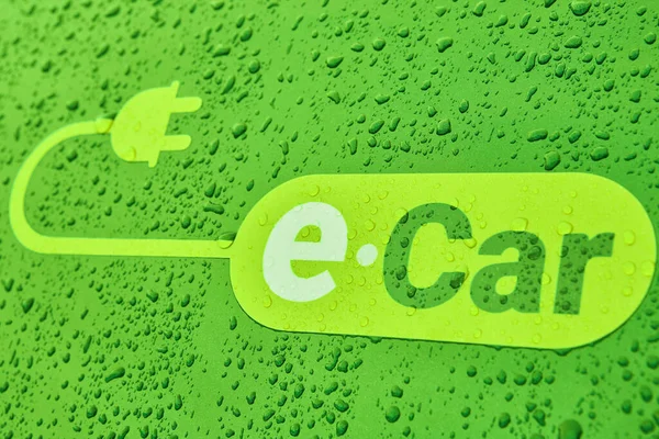 Electric car logo on a car body with rain drops