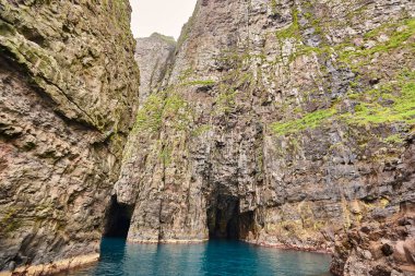 Faroe adalarında Atlantik Okyanusu'nda çarpıcı yeşil kayalıklar ve mağara. 