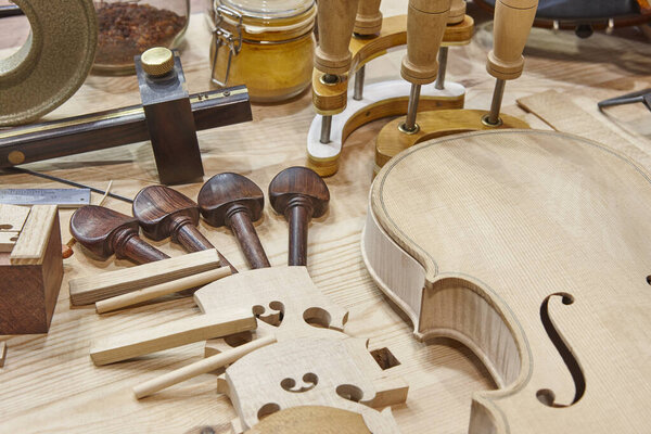 Luthier workshop with violin wooden parts and tools. Traditional craftmanship. 