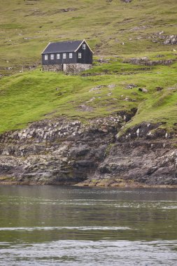 Rocky sahili Faroe yeşili manzarası ve geleneksel resim evi. Nordic