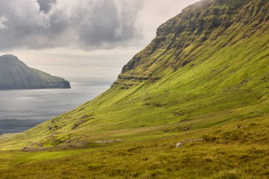 Faroe adalarındaki yeşil çim kayalık tepeler ve fiyortlar. 