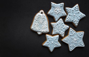 Koyu tabakta kremayla kaplı ev yapımı zencefilli kurabiyeler: çan ve yıldızlar; Noel şekilli lezzetli kurabiyeler