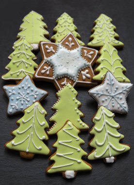 Ev yapımı zencefilli kurabiyeler koyu tabaktaki kremayı kaplıyor: çam ağaçları, kar taneleri ve yıldızlar; Noel şekilli lezzetli kurabiyeler