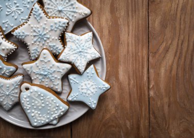 Ahşap arka planda kremayla kaplı ev yapımı zencefilli kurabiyeler, Noel şekilli lezzetli kurabiyeler.