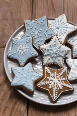 Homemade gingersnaps covered with icing on the wooden background; delicious cookies with Christmas shapes clipart